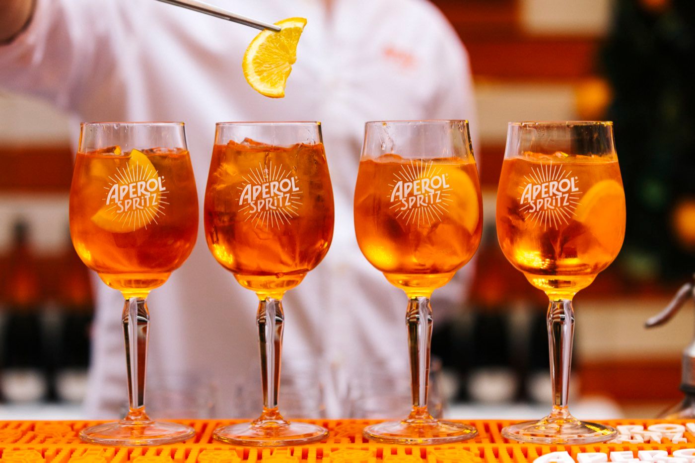 Vier servierfertige Aperol Spritz in einer Reihe beim Open-Air-Event
